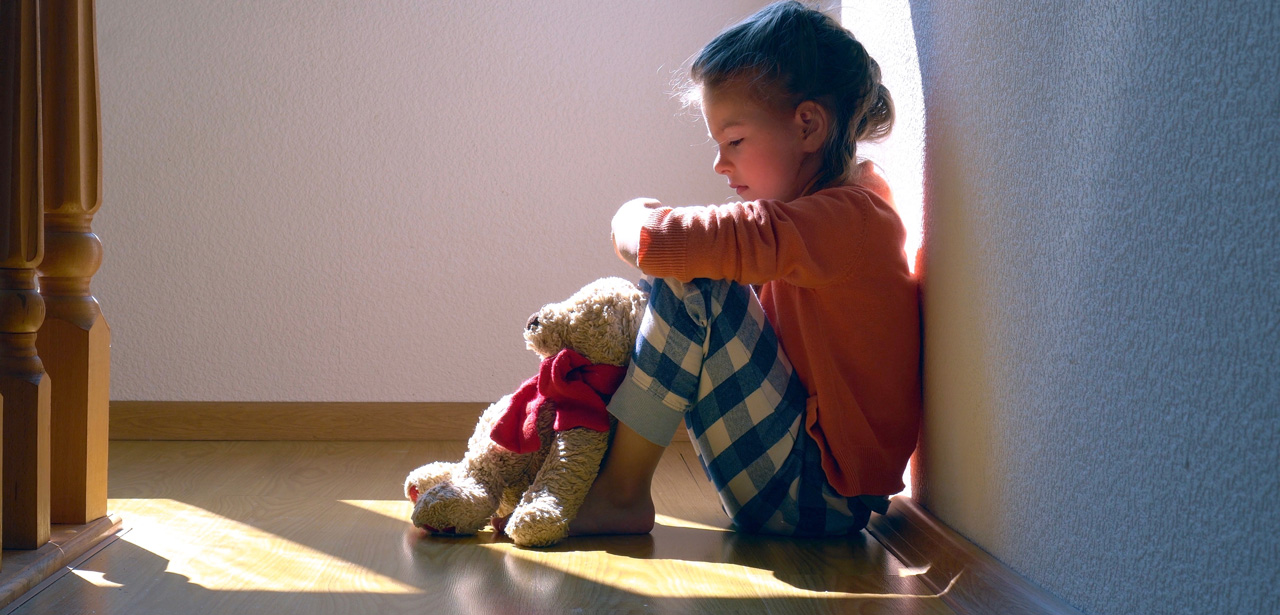 Photo d'une petite fille assise par terre et triste