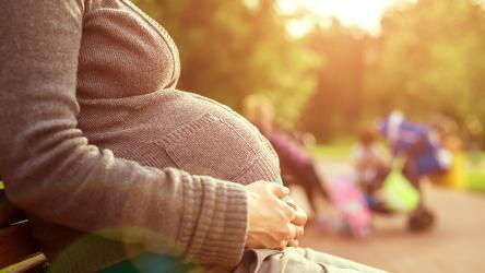 visuel personne enceinte assise sur un bac dans un parc