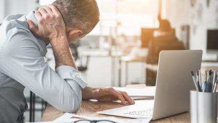 Photographie d'un homme souffrant de cervicalgie au travail