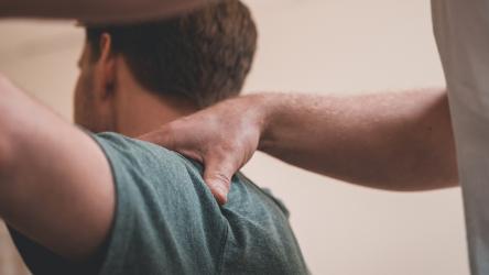 Patient en train de se faire manipuler l'épaule par un professionnel de santé