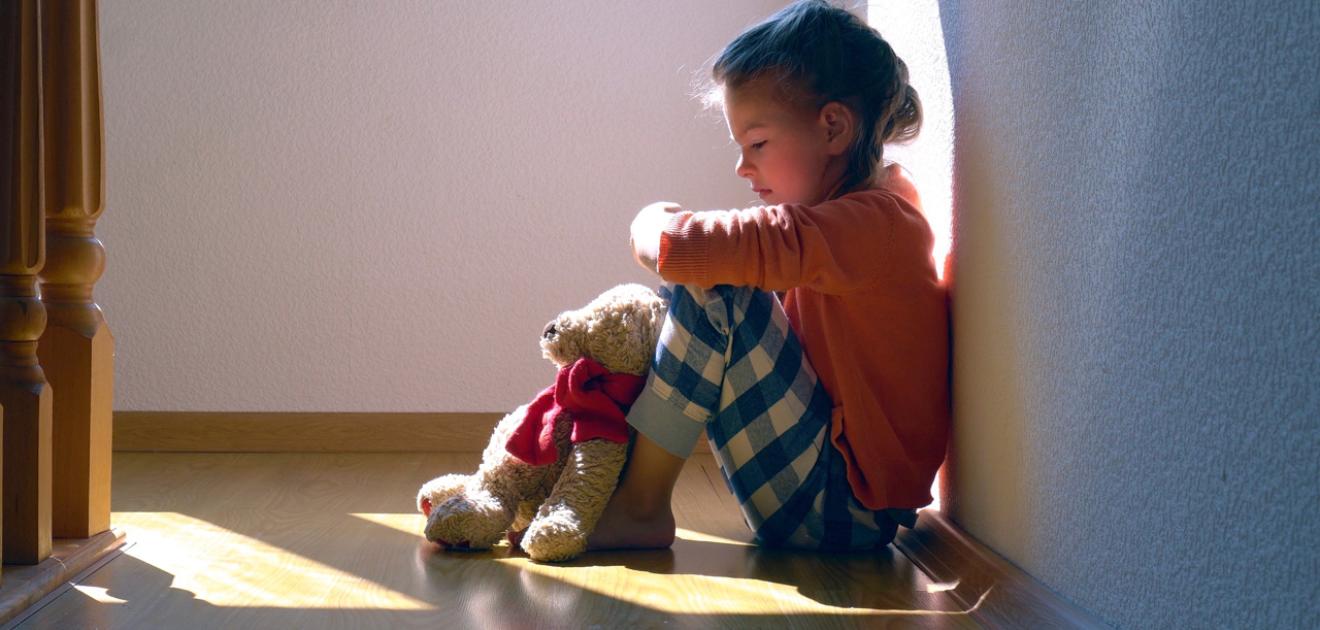 Photo d'une petite fille assise par terre et triste